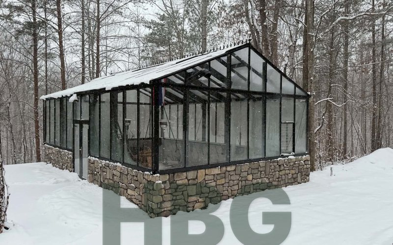 Janssens Gigant Hybrid greenhouse on a natural stone knee wall in a snowy wooded setting in Cleveland County, NC